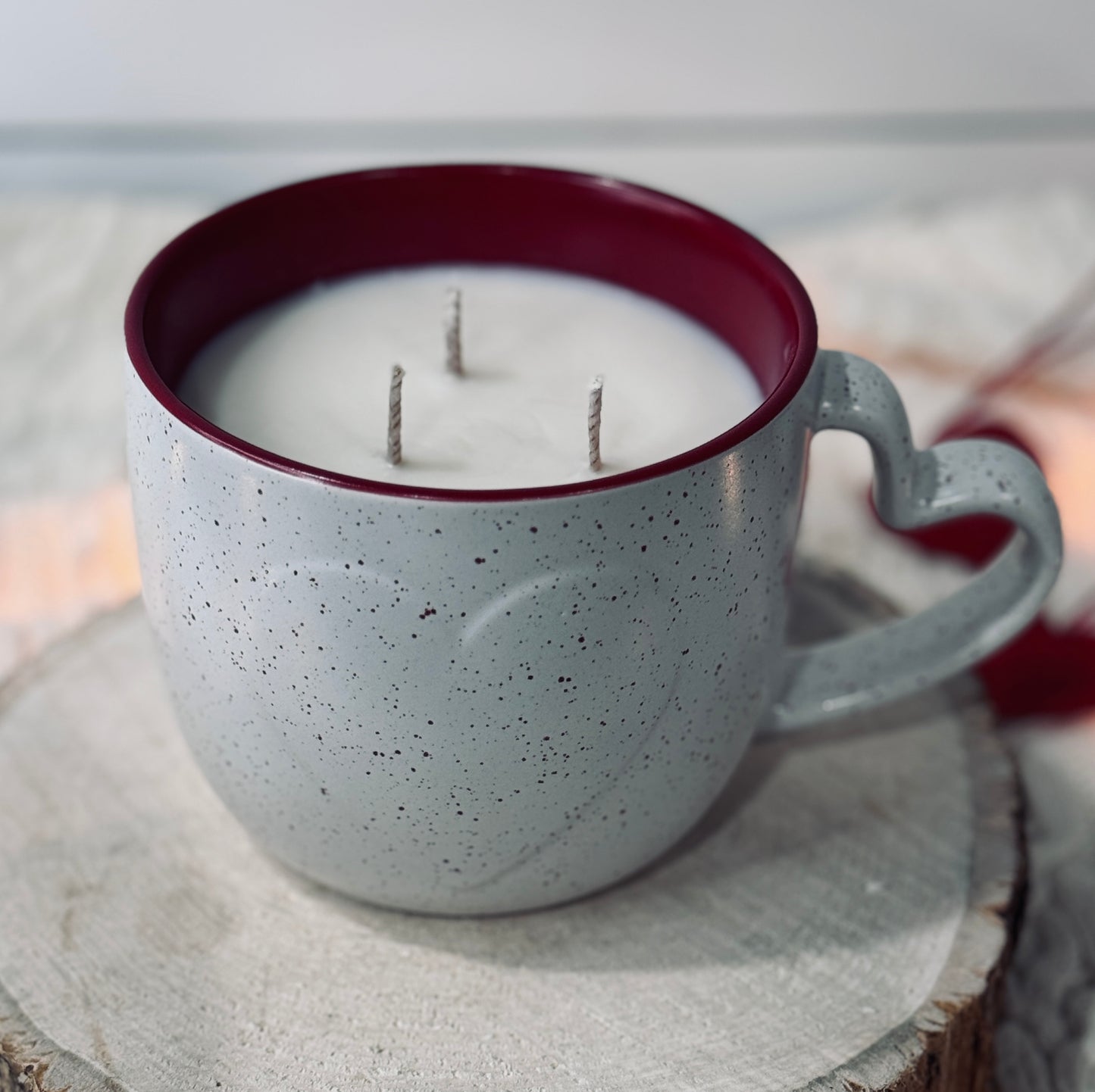 Candle in a large mug with heart on front, heart shaped mug handle, sitting on wood surface