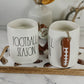 Two white ceramic mugs with 'FOOTBALL SEASON' text, decorated with brown football-shaped handles and placed on a wooden tray with football motifs.