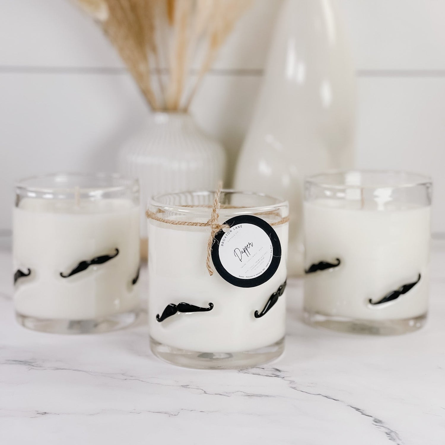 Candle vessels with mustache designs on a marble surface