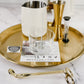 Candle-making tools and materials on a gold tray with a marble surface