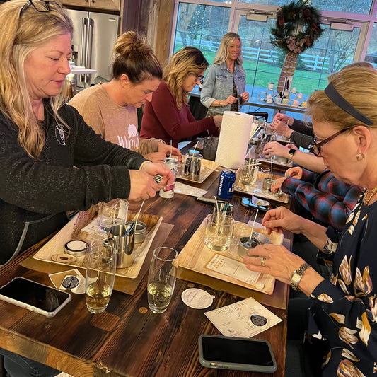 Group of people gathered around a table with wine glasses, in a cozy indoor setting.