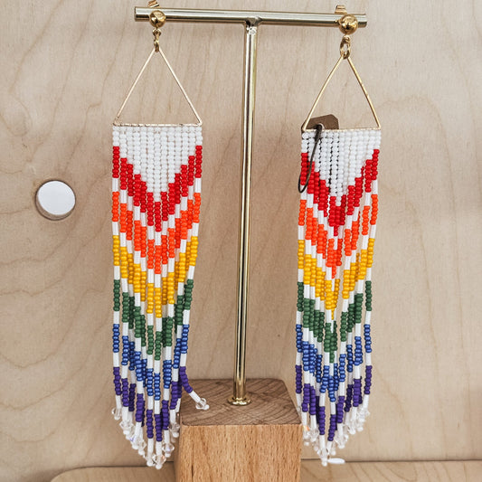 Colorful beaded earrings on a wooden stand against a light wood background